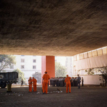 <p>Security forces muster while a team of workers sweep the space beneath the hulking mass of the Museu de Arte de São Paulo.</p>