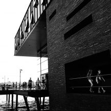 <p>Saturday strollers along the waterfront pass through light and shadows.</p>