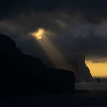 <p>Dramatic skies enhance the view from Kallur back toward the sea stacks off Eysturoy.</p>
