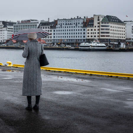 <p>A person stops momentarily on a rainy morning along Bergen's waterfront.</p>