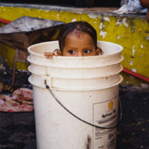 <p>A baby bathes in a plastic bucket. The child's family had been displaced by flooding and they were living in makeshift shelters on a plaza near the national congress.</p>