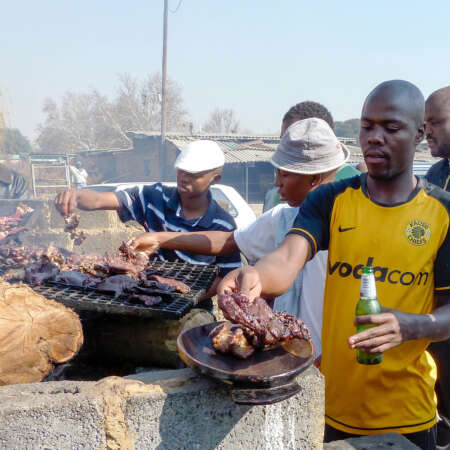 <p>Men concentrate on cooking at a braai in Soweto.</p>