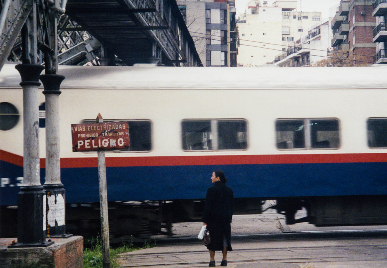 <p>A woman waits at a level crossing in Buenos Aires.</p>