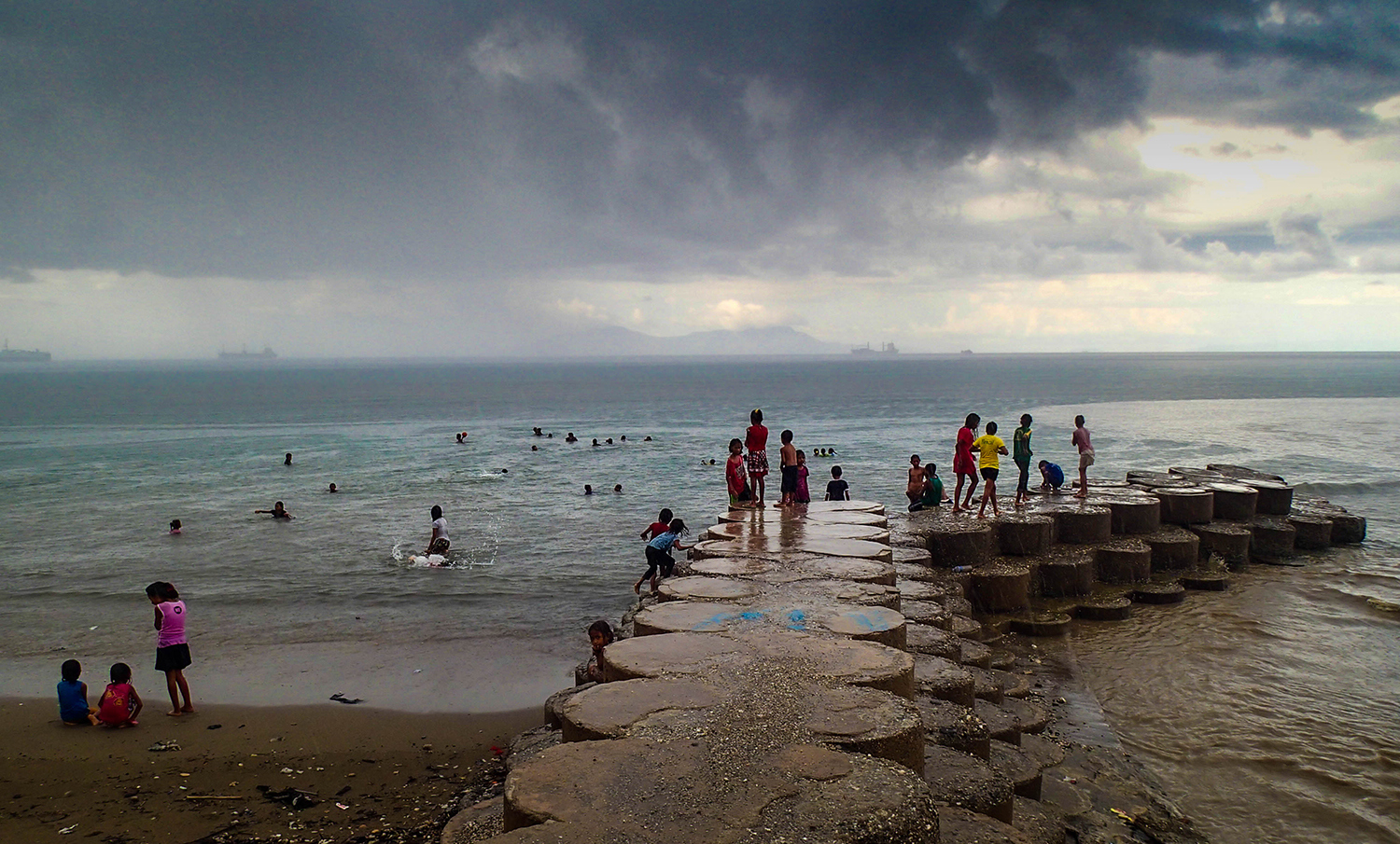 <p>Children playing along Dili's waterfront after the daily rainstorm.</p>